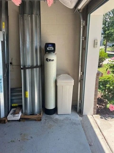 Garage with water softener, storage panels, and open garage door.