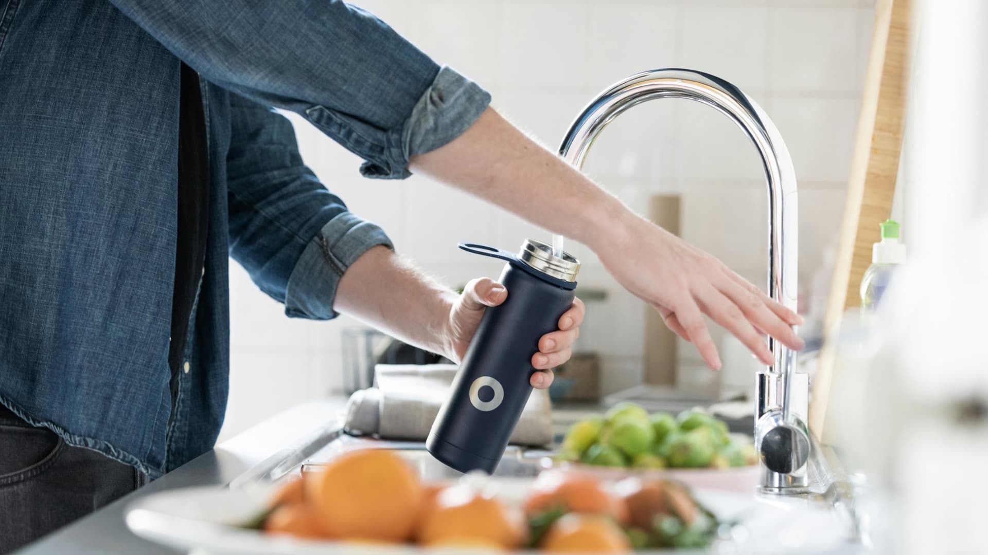 A hand holding a glass of clean filtered water